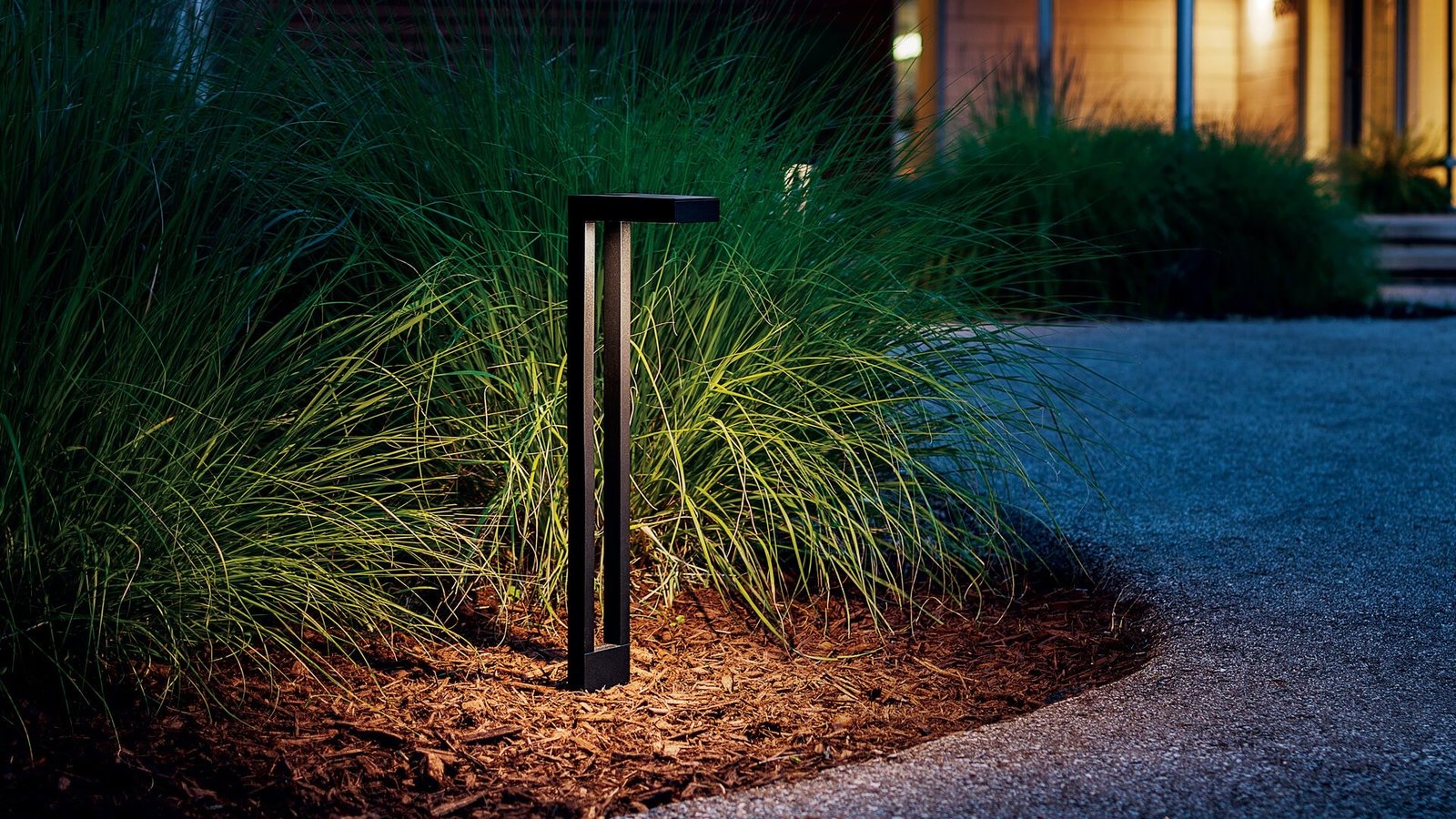 Modern path light beside ornamental grasses