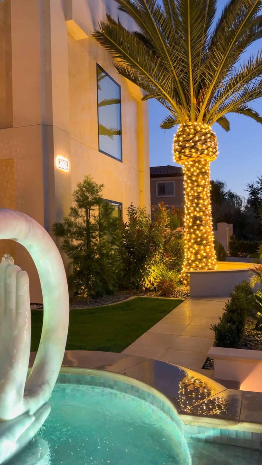 Palm tree and pool lighting beside a modern home