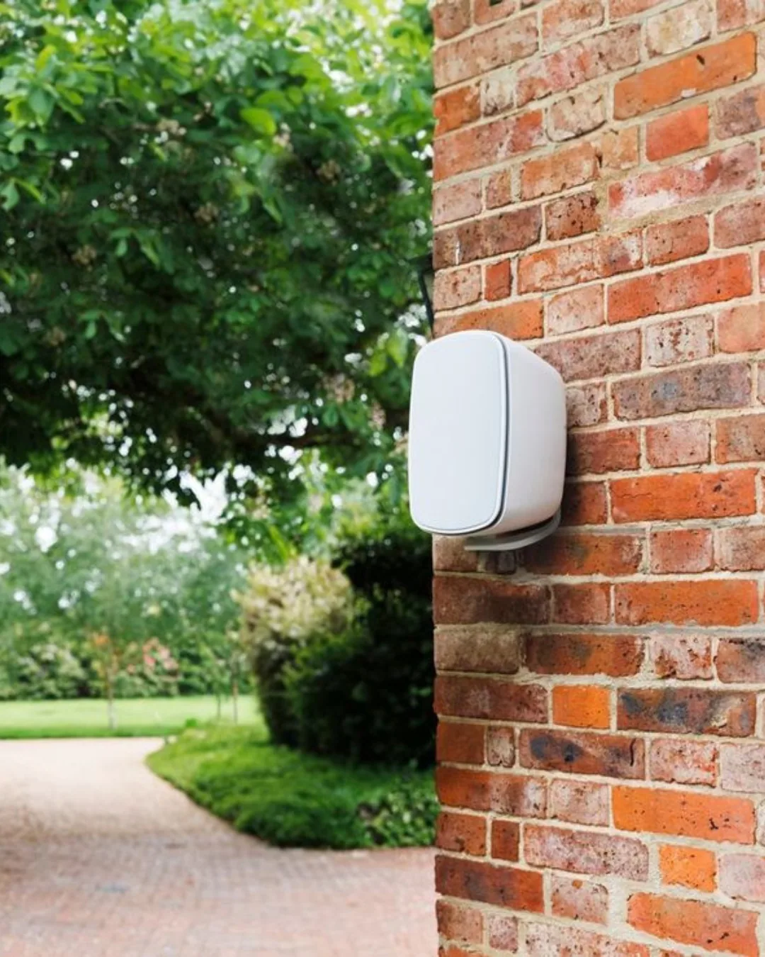 White outdoor speaker mounted cleanly on a brick patio wall